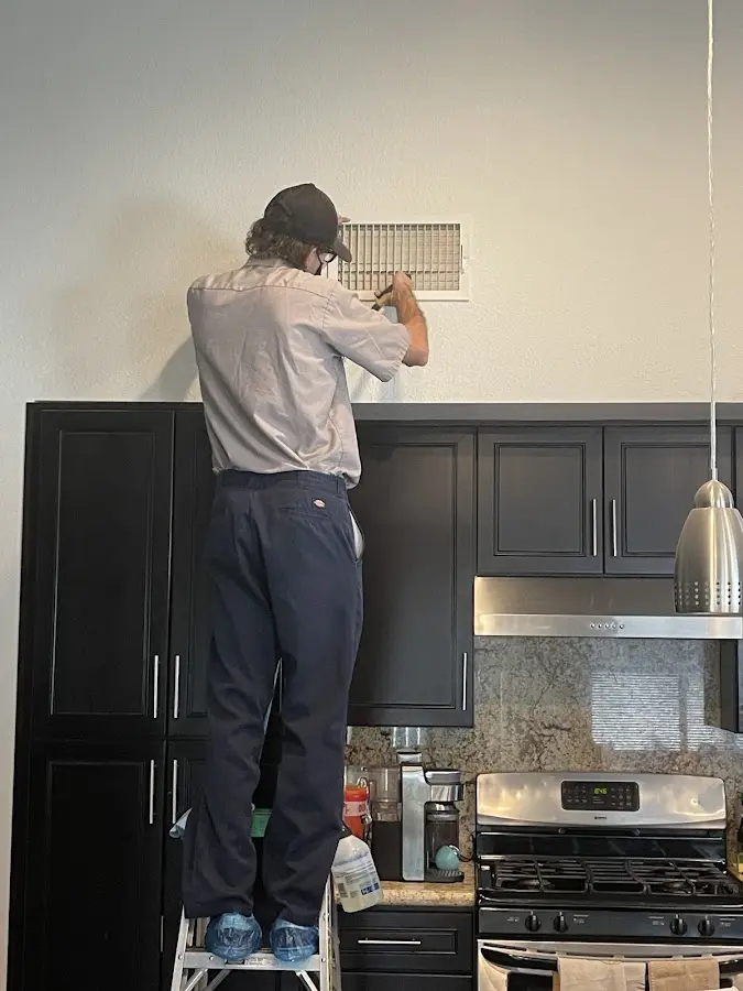 Technician inspecting an air vent during HVAC service in Clarkston